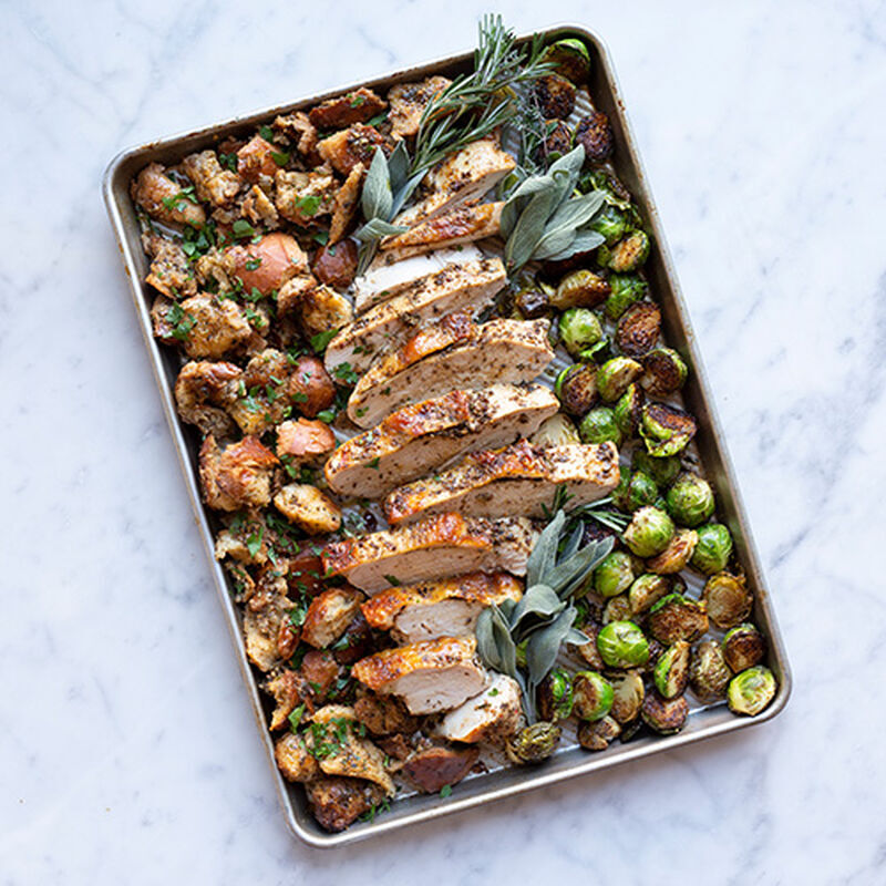Baking pan filled with roasted turkey slices, vegetables and herbs