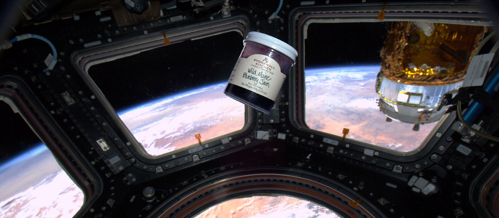 Photo of a Wild Maine Blueberry Jam floating in a spacecraft overlooking the curvature of the earth from space