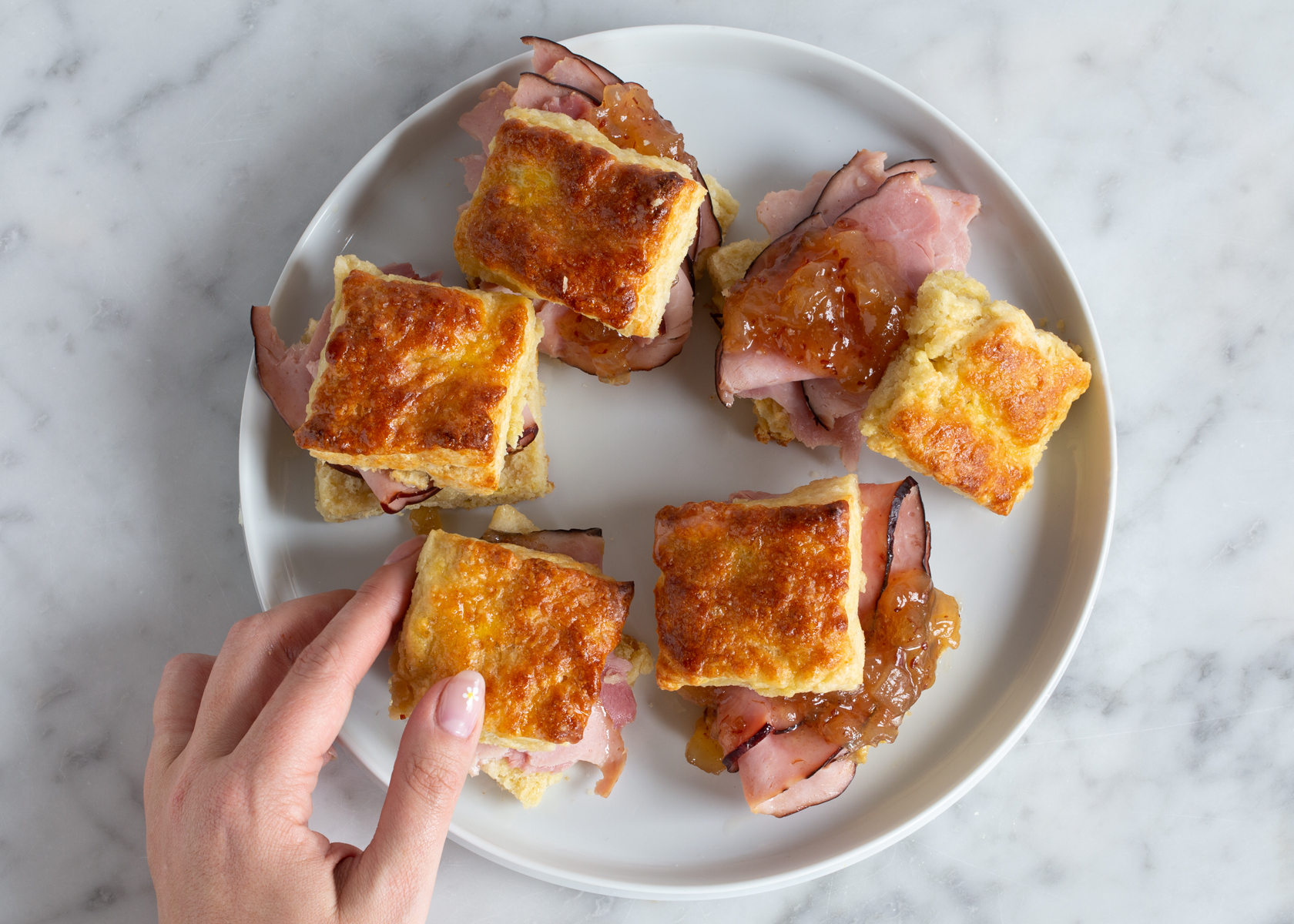 Five small sandwiches on a white plate