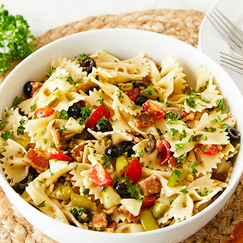 image of a white bowl of greek pasta salad on a serving tray