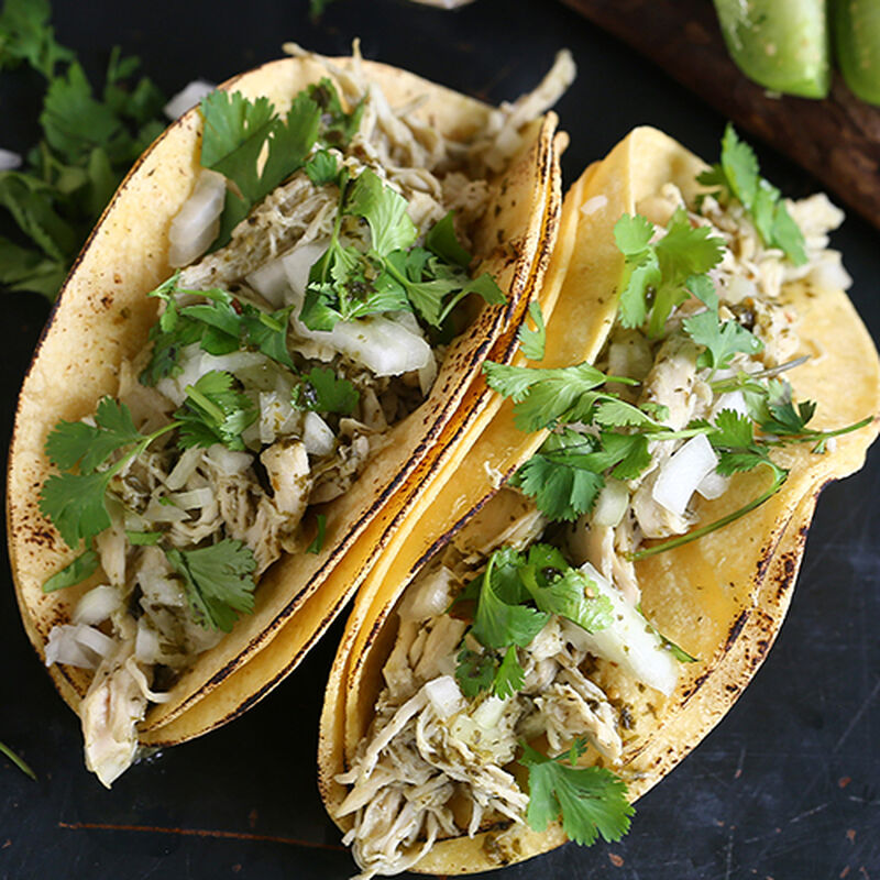 two chicken tomatillo tacos on a dark counter