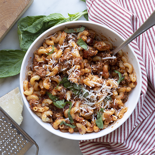 a bowl of chili mac sitting on a printed cloth napkin and counter