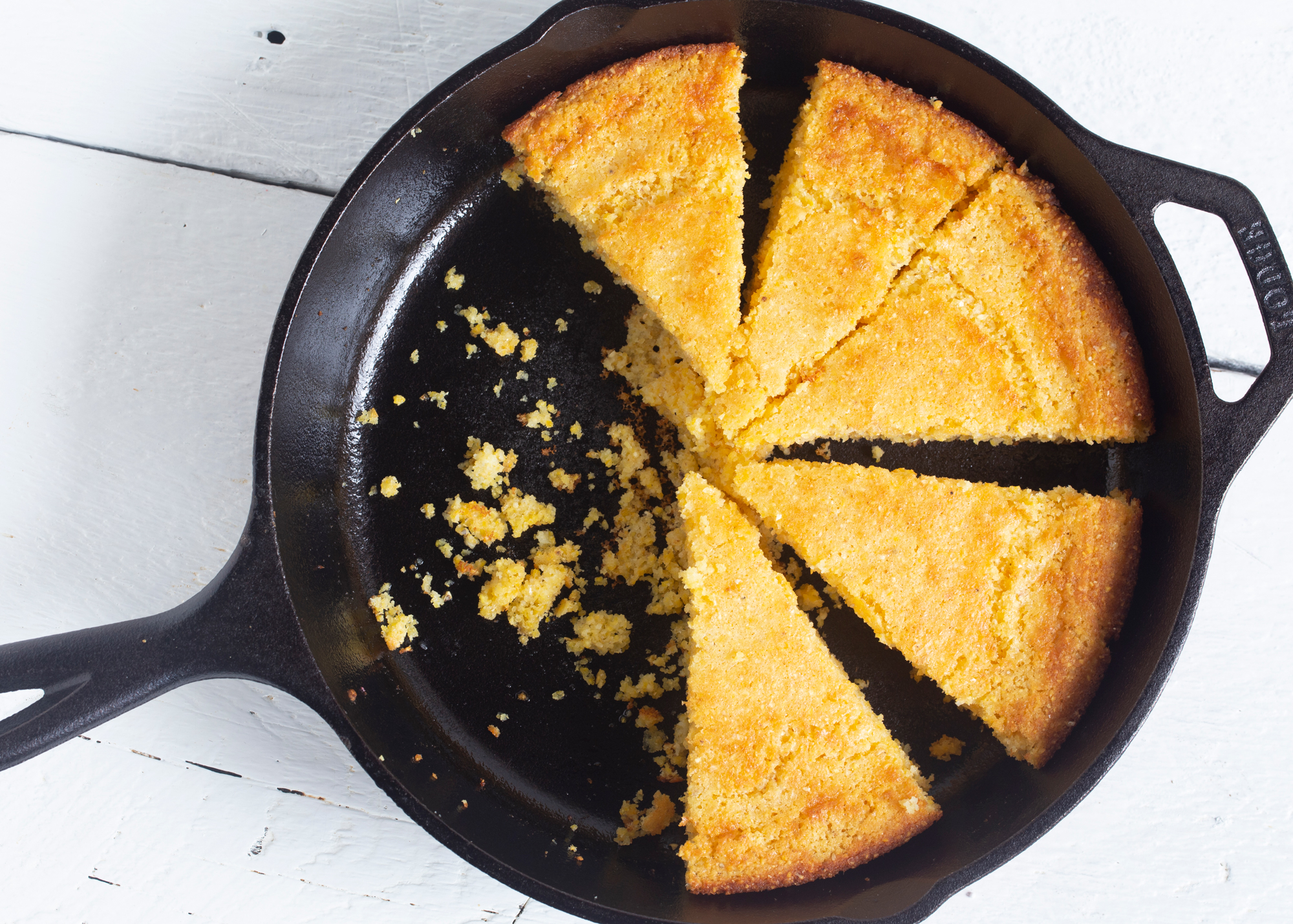 image of some slices of cornbread sitting in a partially empty cast iron skillet on a counter
